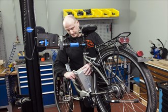 Two-wheeler mechanic in the bicycle workshop during an inspection on an e-bike
