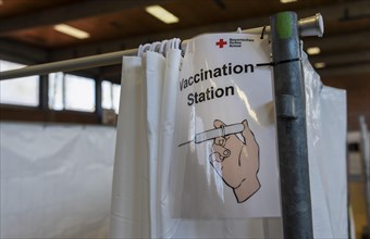 Sign with English inscription VACCINATION STATION hangs in a vaccination center in Erding