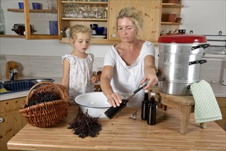 Woman and girl cooking elderberry juice