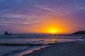 Groyne and diving gondola with pier at the beach of Zingst at sunrise