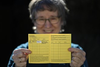 Woman proudly showing her vaccination certificate after being vaccinated with AstraZeneca against Covid-19