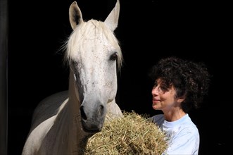 Woman feeds horse with hay