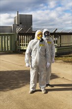 People in protective suits and wearing gas masks demonstrate in front of the former nuclear power plant Wuergassen