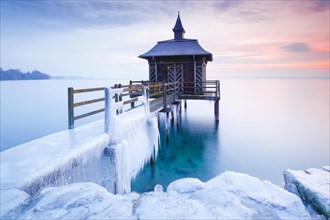 Iced wooden bathhouse at sunrise on Lake Neuchatel in Gorgier
