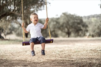 Cute happy blond toddler on the swing