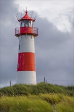 Red-white lighthouse List-Ost in the dunes in front of dark sky