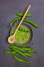Green peas in pod with cooking spoon