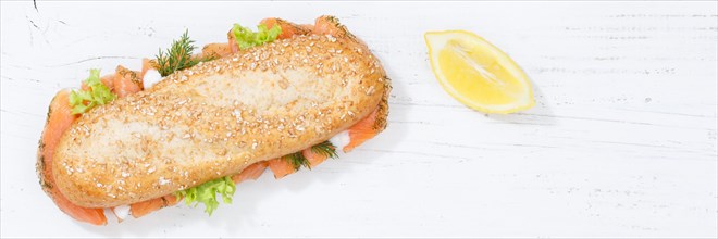 Sandwich baguette wholemeal roll topped with salmon fish banner text free space from top on