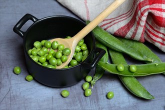 Green peas in pots and cooking spoon