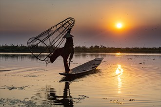 Fisherman at Inle Lake with traditional Intha conical net at sunset