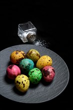 Colored quail eggs on plate and salt shaker