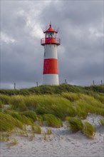 Red-white lighthouse List-Ost in the dunes in front of dark clouds