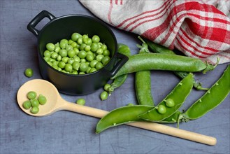 Green peas in pots and cooking spoon