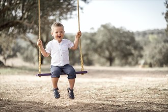 Cute happy blond toddler on the swing