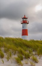 Red-white lighthouse List-Ost in the dunes in front of dark clouds