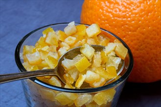 Candied orange peel cubes in glass with spoon