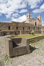 Stone throne in front of the Inca Sun Temple with attached cathedral from the colonial period