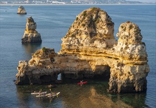 Kayakers paddling around rock formations in the sea