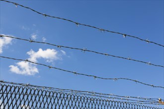 Barbed wire in front of a blue sky