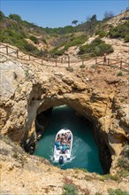 Excursion boat in the turquoise sea passes through rock caves and rock arches