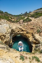 Excursion boat in the turquoise sea passes through rock caves and rock arches