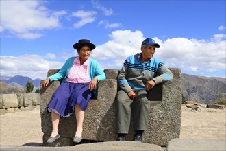 Old indigenous couple sitting on the throne of the Inca on the pyramid