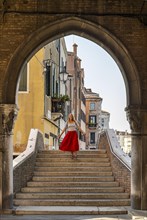 Young woman with red skirt walks through archway