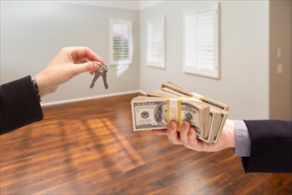 Real estate agent hands over new house keys for cash inside empty room