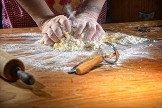 Cook kneading pasta dough on wooden table