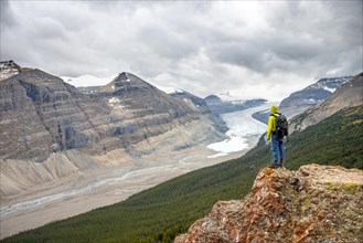 Hiker standing on rocks overlooking valley with glacier tongue