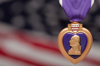 Purple heart against a blurry american flag