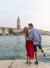Young couple in love standing by the sea enjoying view of St. Mark's Square with Campanile di San Marco