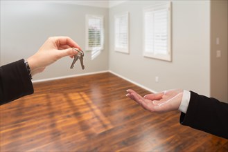 Real estate agent hands over new house keys inside empty room