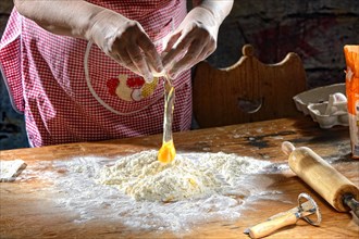 Cook making pasta dough on wooden table