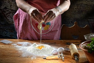 Woman beats egg on flour for pasta dough