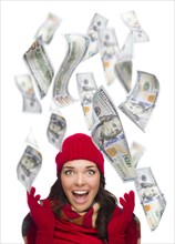 Young excited warmly dressed woman with $100 bills falling money around her on white