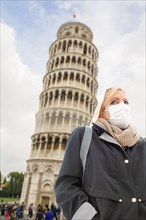 Young Woman Wearing Face Mask Walks Near The Leaning Tower of Pisa In Italy