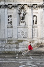 Young woman with red dress in front of white church