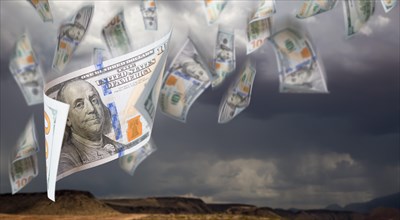 Several 100 dollar bills falling from stormy cloudy sky