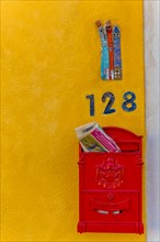Letterbox and house number on a yellow house wall