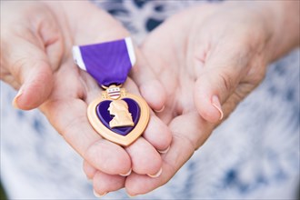 Senior woman holding the United States military purple heart medal in her hands
