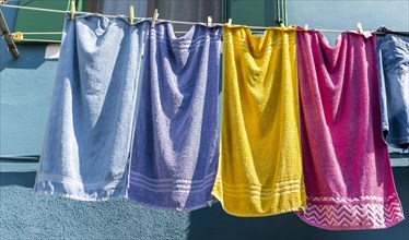 Colorful laundry on clothesline in front of blue house wall