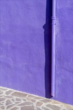 Purple house wall with gutter