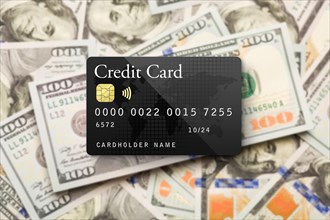 Mockup black credit card resting on one hundred dollar bills background