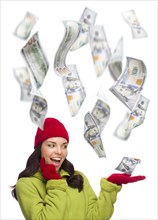 Young excited warmly dressed woman with $100 bills falling money around her on white