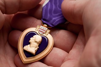 Man holding United States purple heart war medal in the palm of his hand