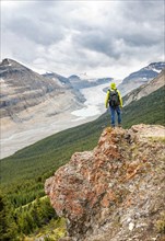 Hiker standing on rocks overlooking valley with glacier tongue