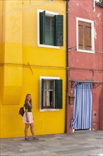 Young woman in front of colorful house