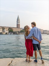 Young couple in love standing by the sea enjoying view of St. Mark's Square with Campanile di San Marco