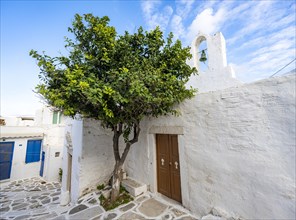 Small white Greek Orthodox chapel with green tree